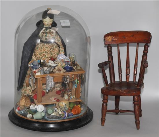 A Regency painted wood doll and accessories under glass dome and a miniature chair
